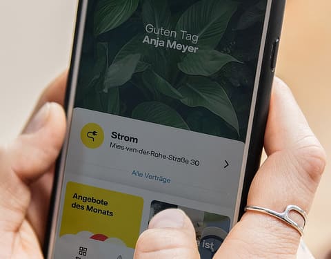 Hand hält Smartphone. Auf dem Bildschirm ist die geöffnete Vattenfall-App zu erkennen.